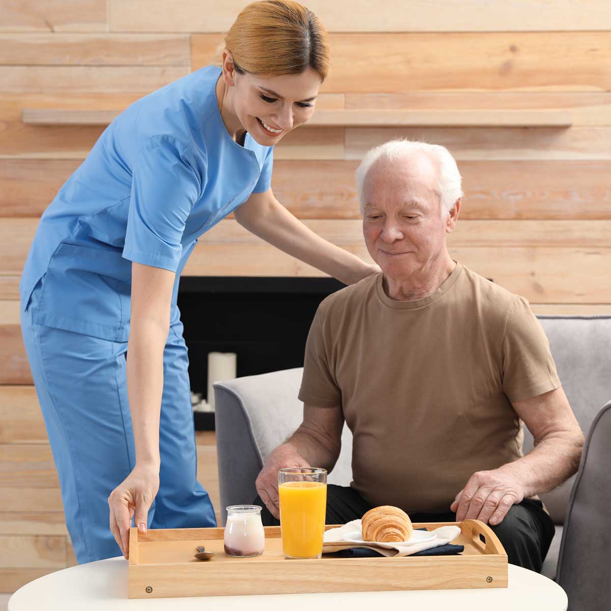 Home care visiting nurse in Saline County serving breakfast to a smiling elderly man in a cozy home setting